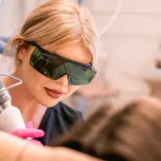 Kosmetolog w okularach ochronnych wykonuje epilację laserową. Dowiedz się, epilacja laserowa co to i jak działa.